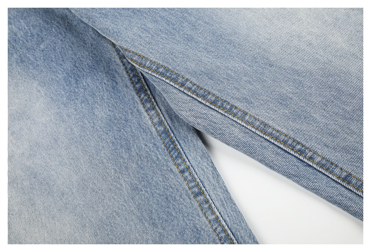 Close-up of light blue jeans showing the inner-leg seam and double rows of contrast stitching.