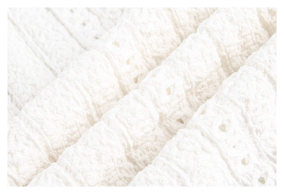 Macro view of the white textured garment's raised pattern and small eyelet openings.