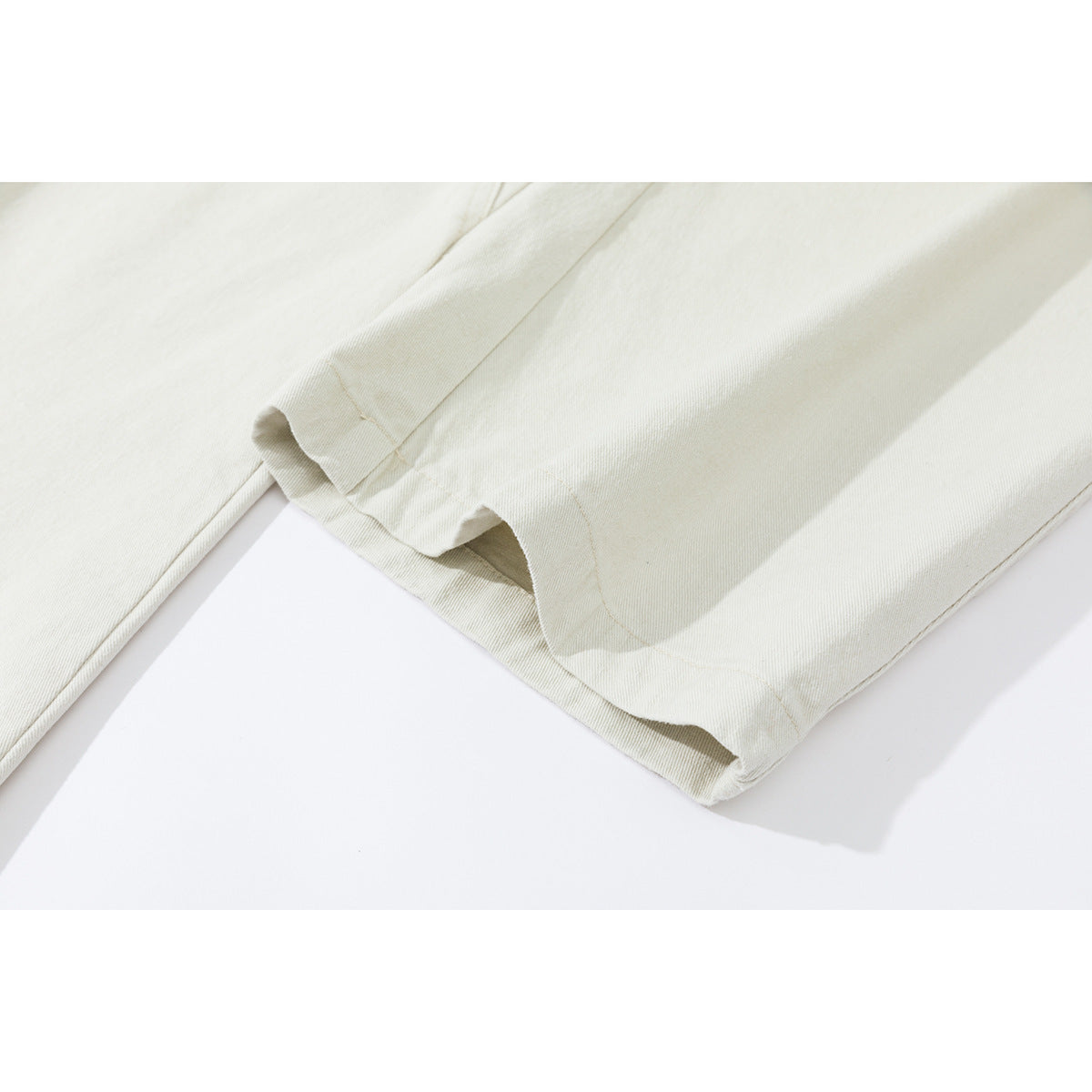 Close-up of the stitched hem and seams on ivory pants.