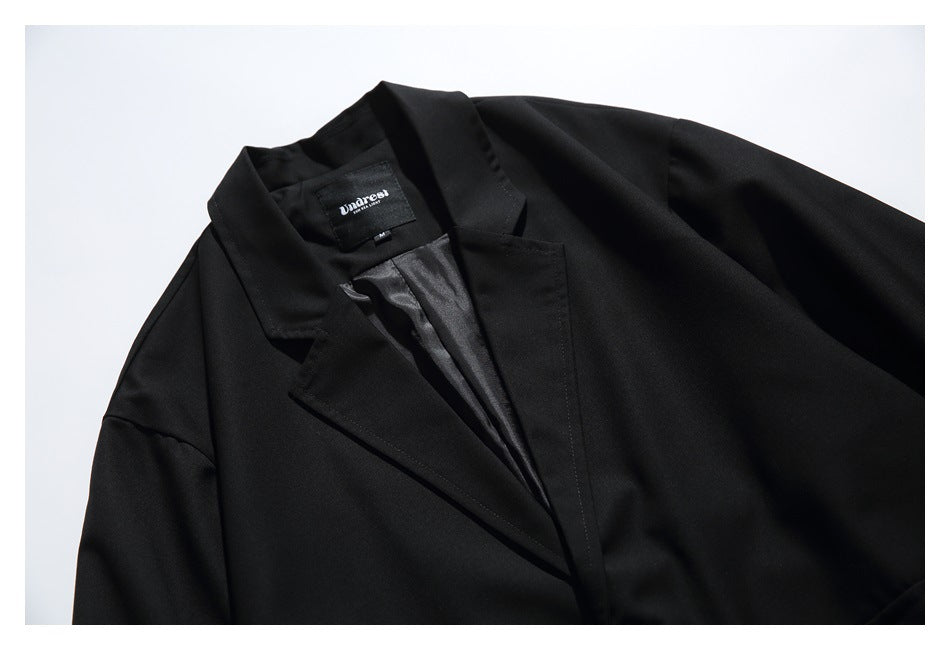 Close-up of a black blazer's notched lapels, open front, dark lining, and sewn neck label.
