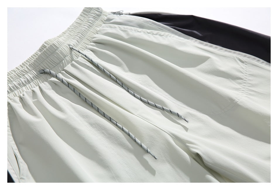 Detail of light-colored shorts with a gathered waistband, patterned drawcords and dark inner lining.