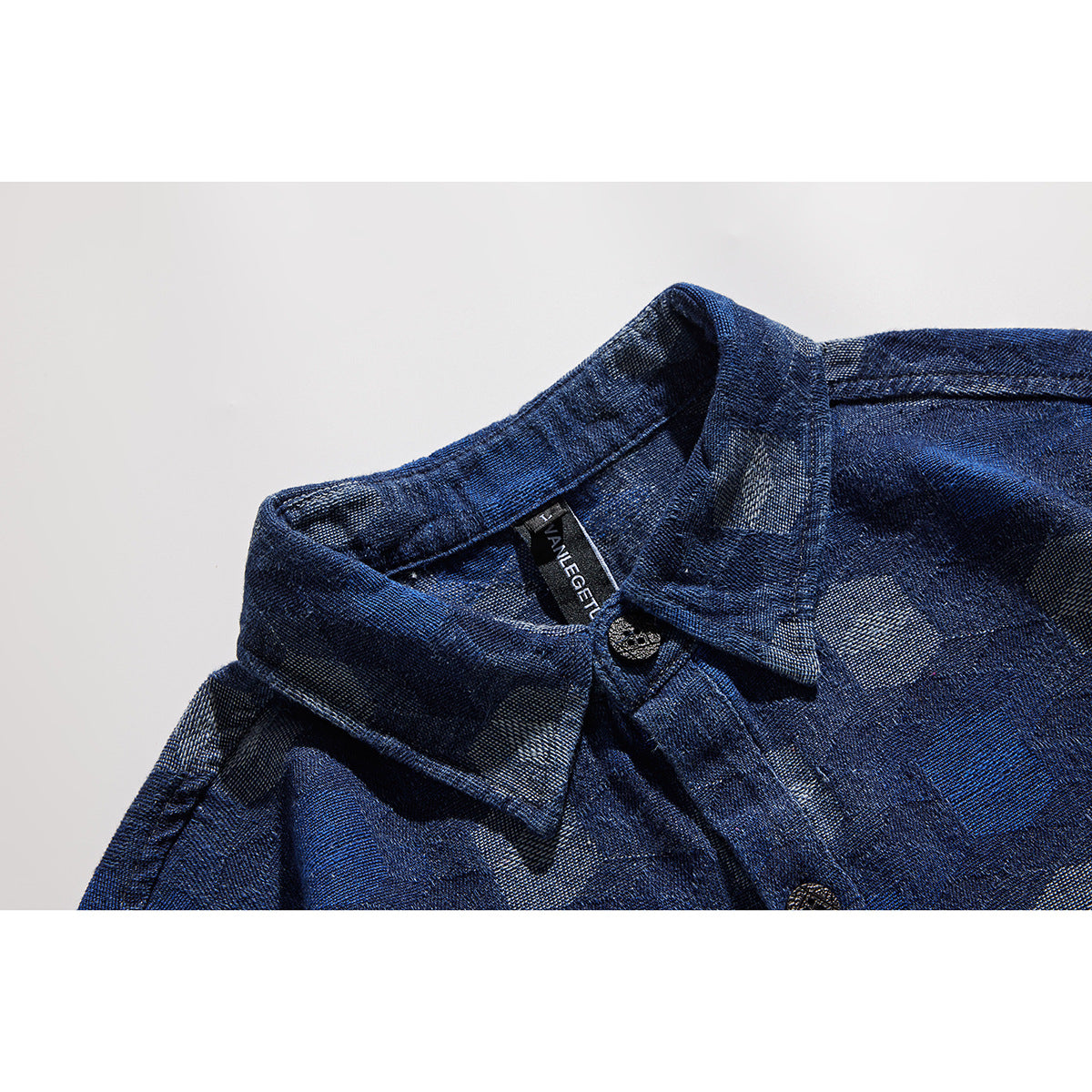 Close-up of the dark blue patterned shirt collar, button, and inner neck label.