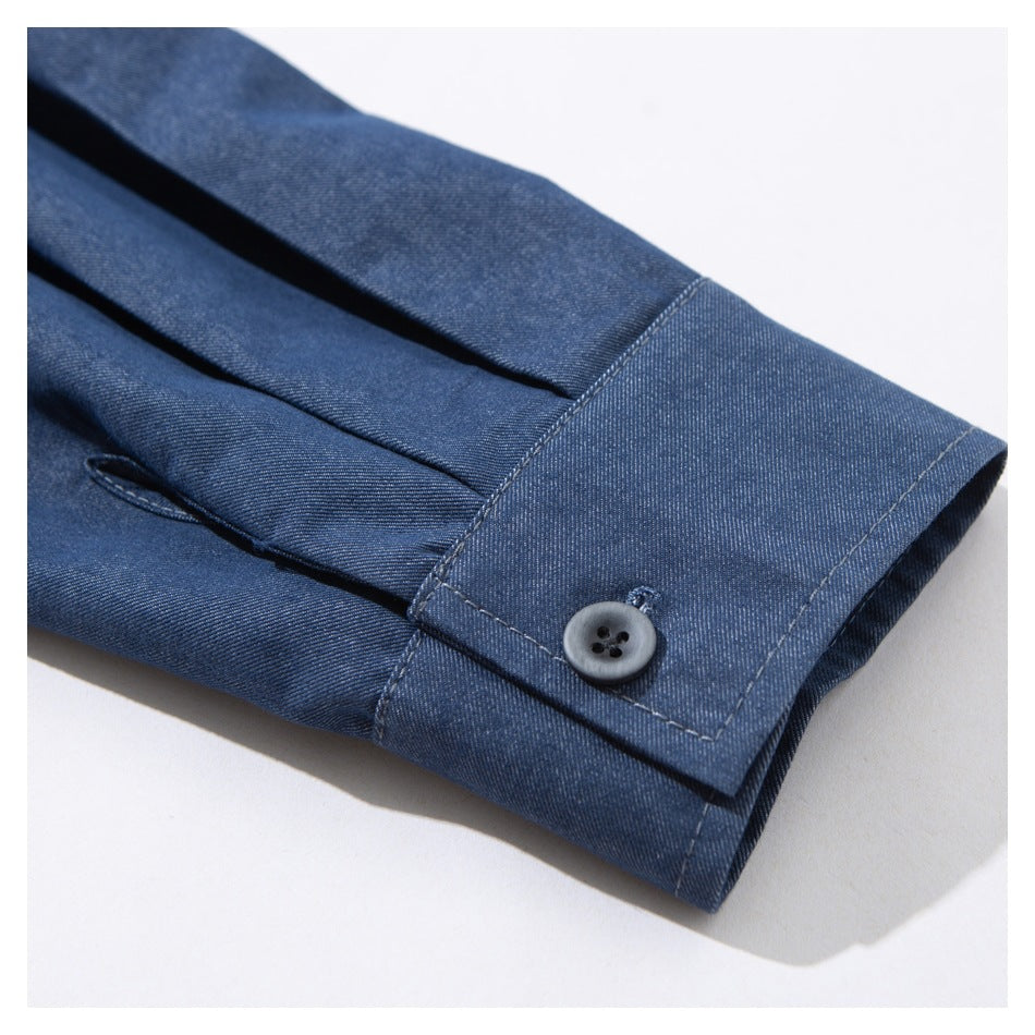 Close-up of a blue shirt sleeve cuff with a gray button and neat stitching.