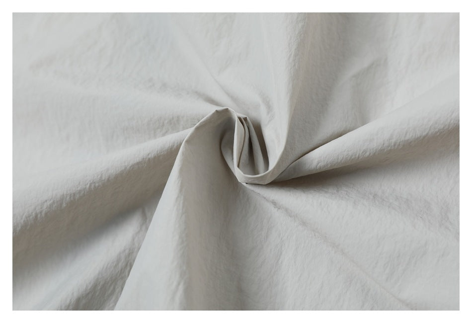 Close-up of light gray woven fabric gathered into soft folds.