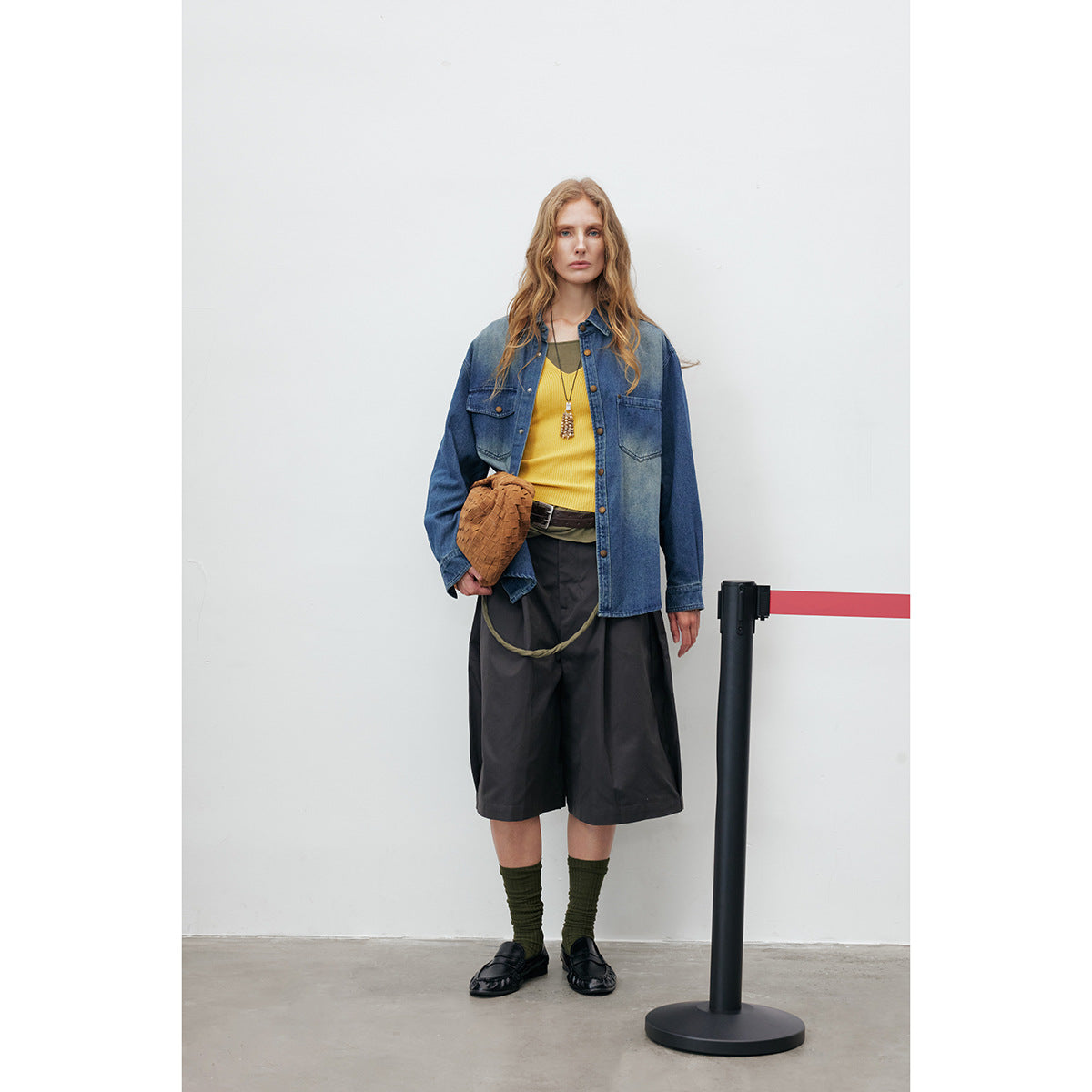 Full-length front view of a model in an oversized blue denim button-up shirt with chest pockets.