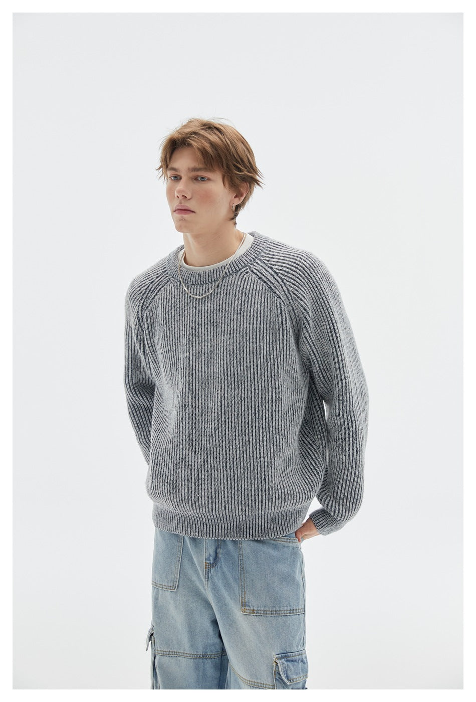 Front view of a model wearing a light gray ribbed crewneck sweater with raglan sleeves and light blue jeans.