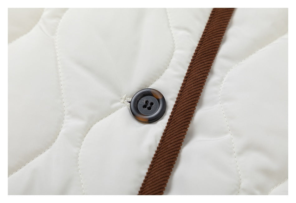 Close-up of a dark button and brown corduroy front trim against ivory quilted fabric.