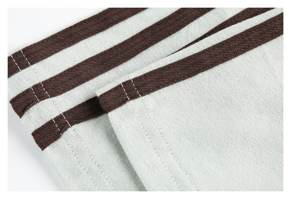 Close-up of brown stripe trim and stitched seams on pale gray fabric.