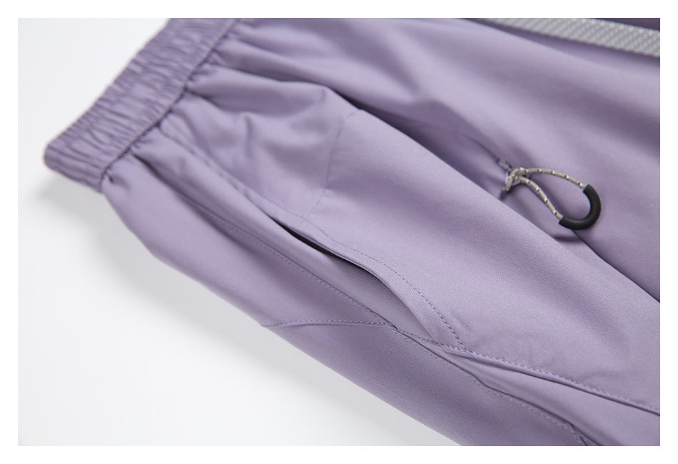 Close-up of lavender trousers showing a slanted pocket and a small black loop attached to a cord.