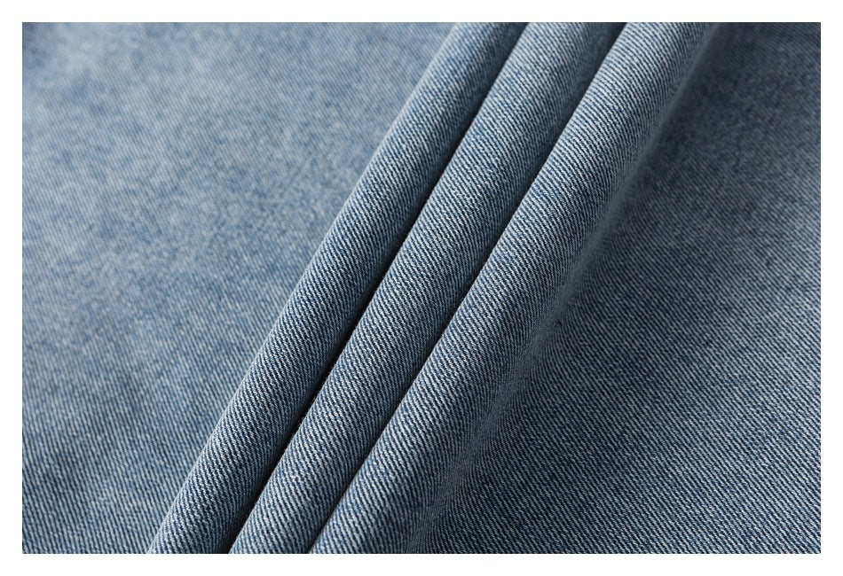 Extreme close-up of light blue denim fabric folded to show its diagonal weave and washed texture.