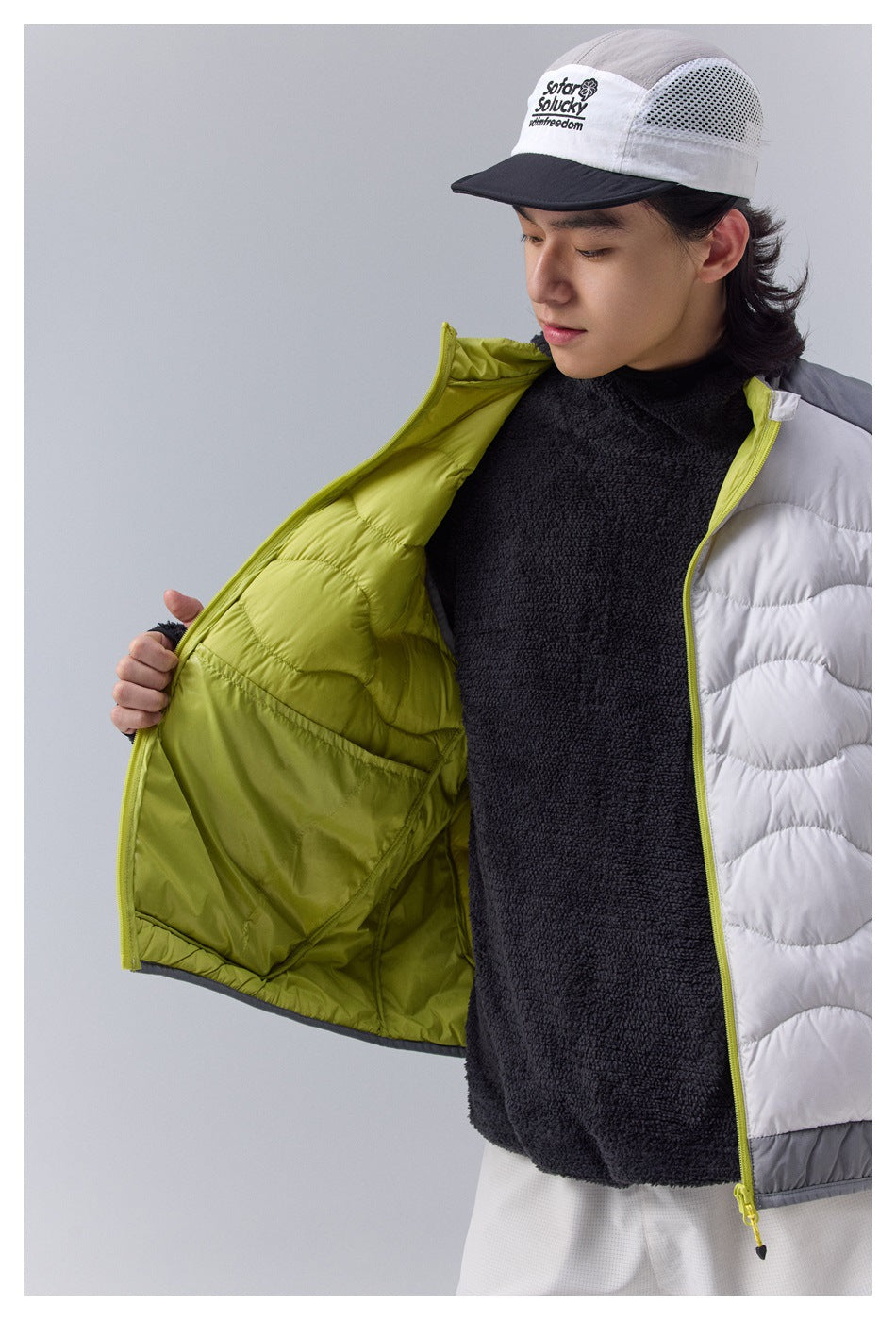Close-up shows the white vest opened to reveal its lime-green quilted interior, zipper and pocket construction.