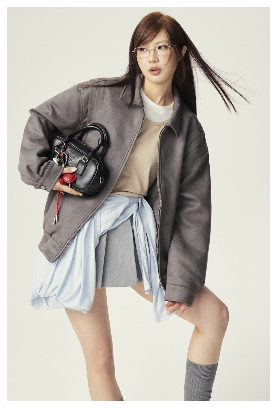 Model wearing an oversized gray zip jacket with a beige top and gray skirt.