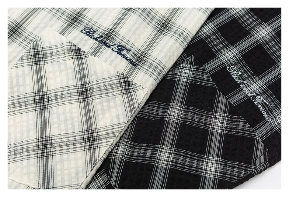 Close-up of black and ivory plaid hooded shirts, showing their contrasting checks and script embroidery.
