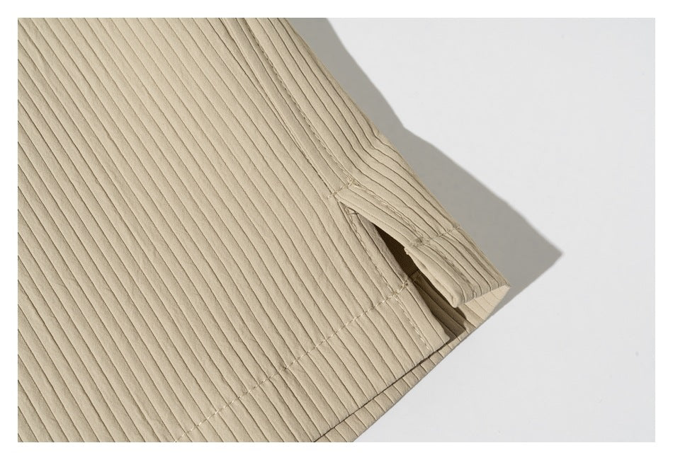 Close-up of a beige ribbed garment hem with a short side slit and visible stitching.