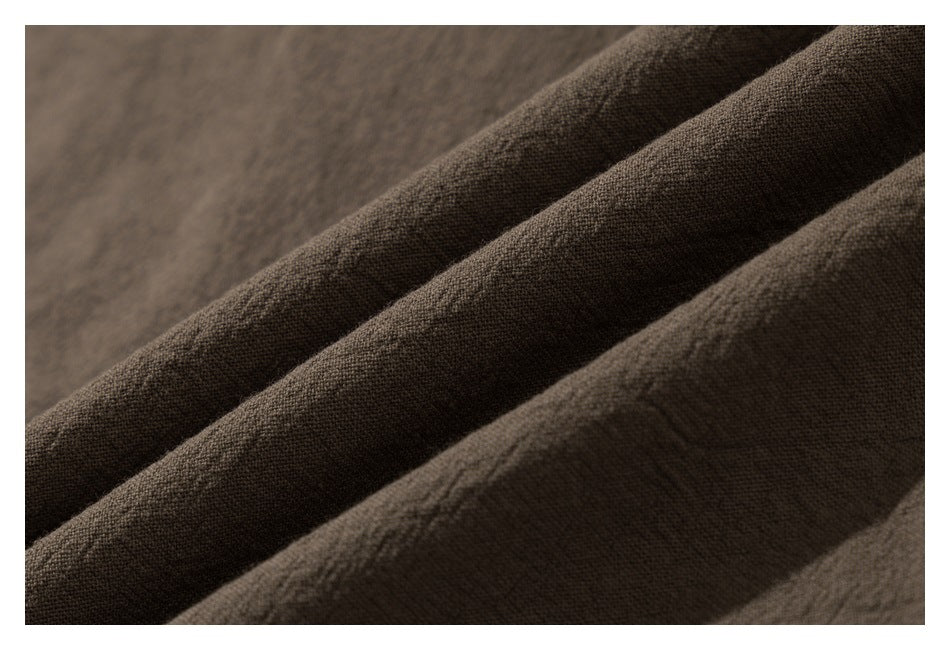 Close-up of dark brown textured knit fabric arranged in soft folds.