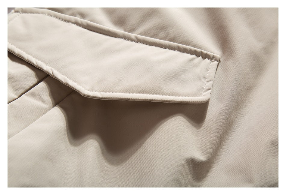 Close-up of a beige jacket's flap pocket and stitched edge.