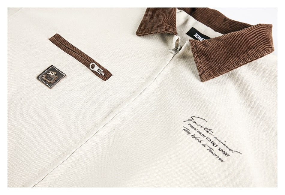 Close-up of an ivory jacket front with brown collar and zipper accents, a small patch, and printed script.