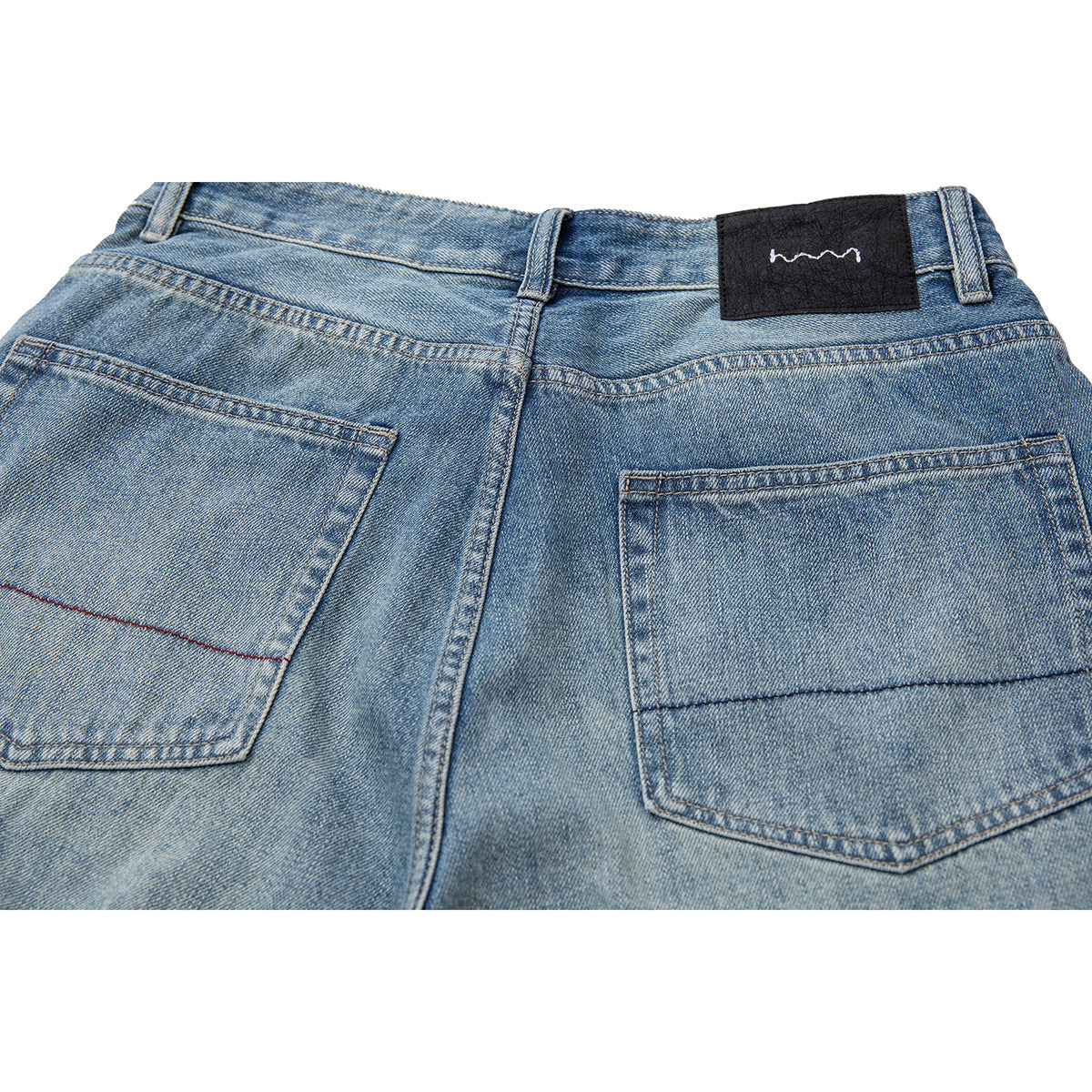 Close-up of the back waistband and two pockets on light blue denim shorts.