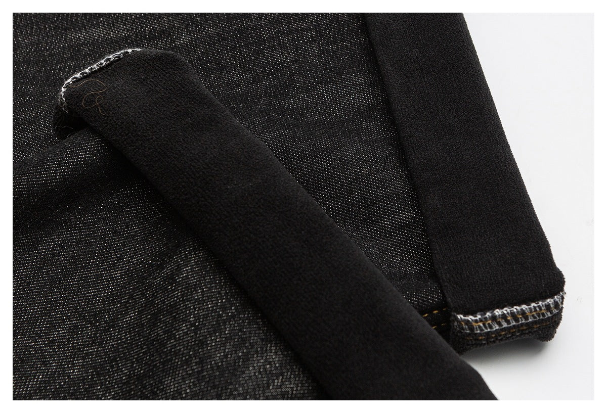 Close-up of black denim with folded fabric edges and visible overlock stitching on the underside.