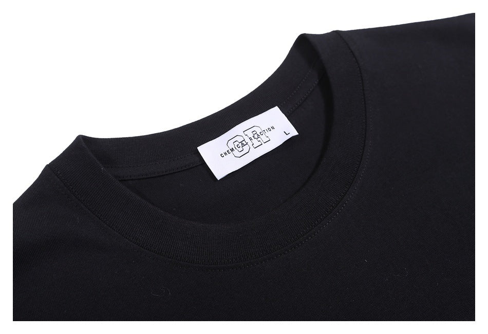 Close-up of the black T-shirt's ribbed crew neck and a small white sewn-in label.