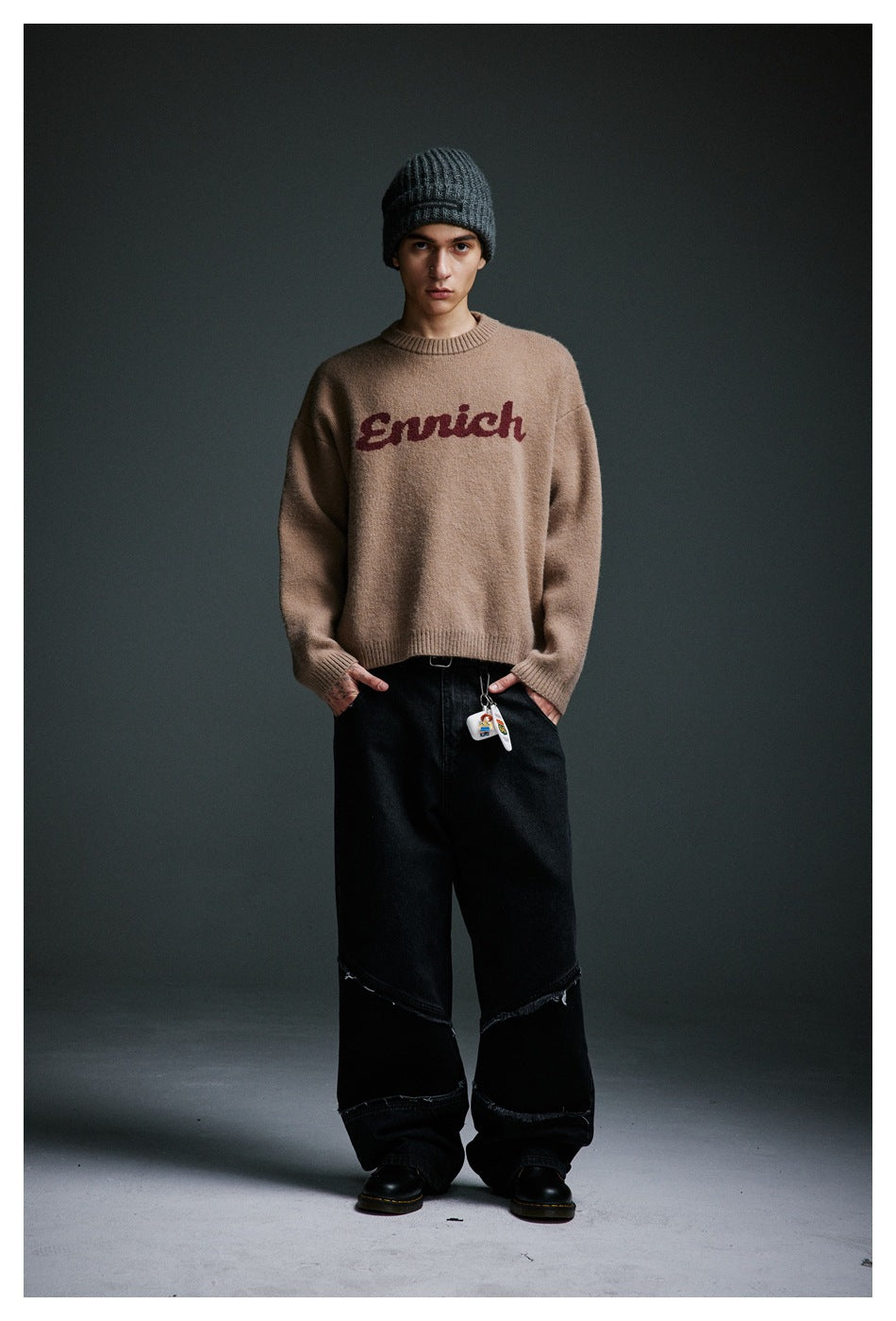 Model wearing camel Enrich knit sweater with gray beanie and black wide-leg jeans, front view