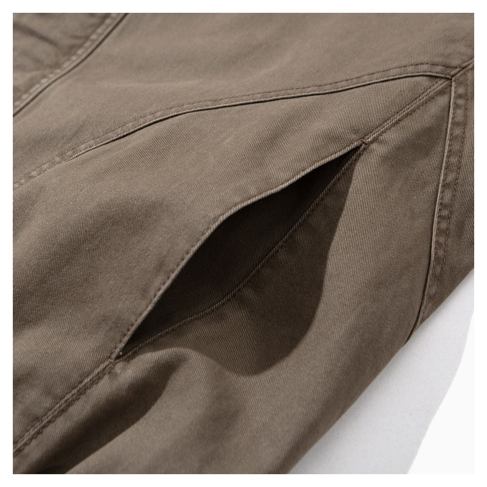 Close-up of a brown jacket's angled pocket opening and stitched seams.
