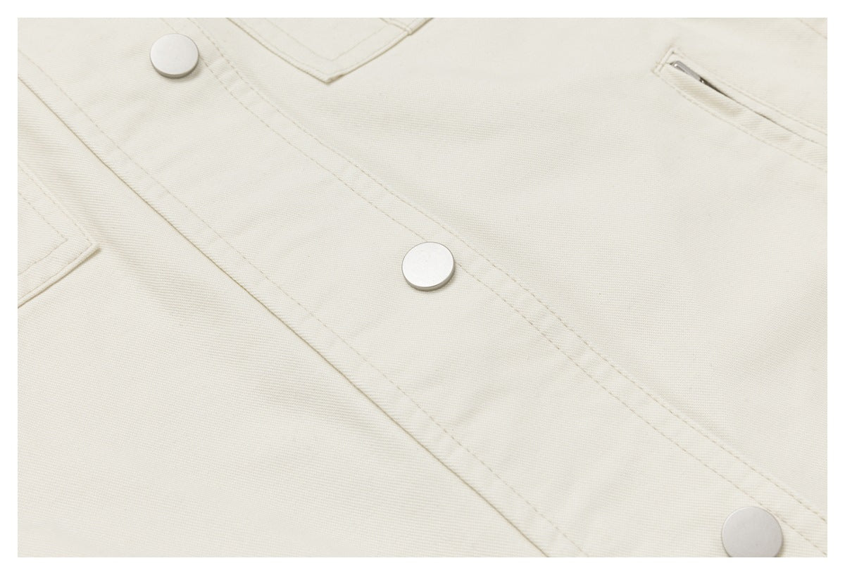 Close-up of an ivory garment's snap-button front placket and zippered pocket.