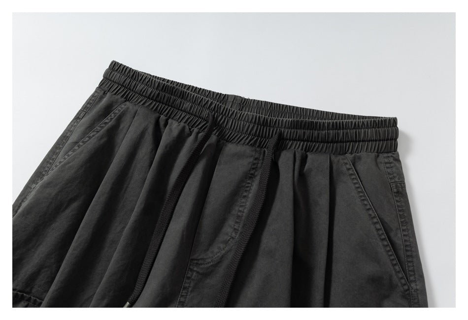 Close-up of black wide-leg shorts showing the elastic drawstring waistband and angled front pockets.
