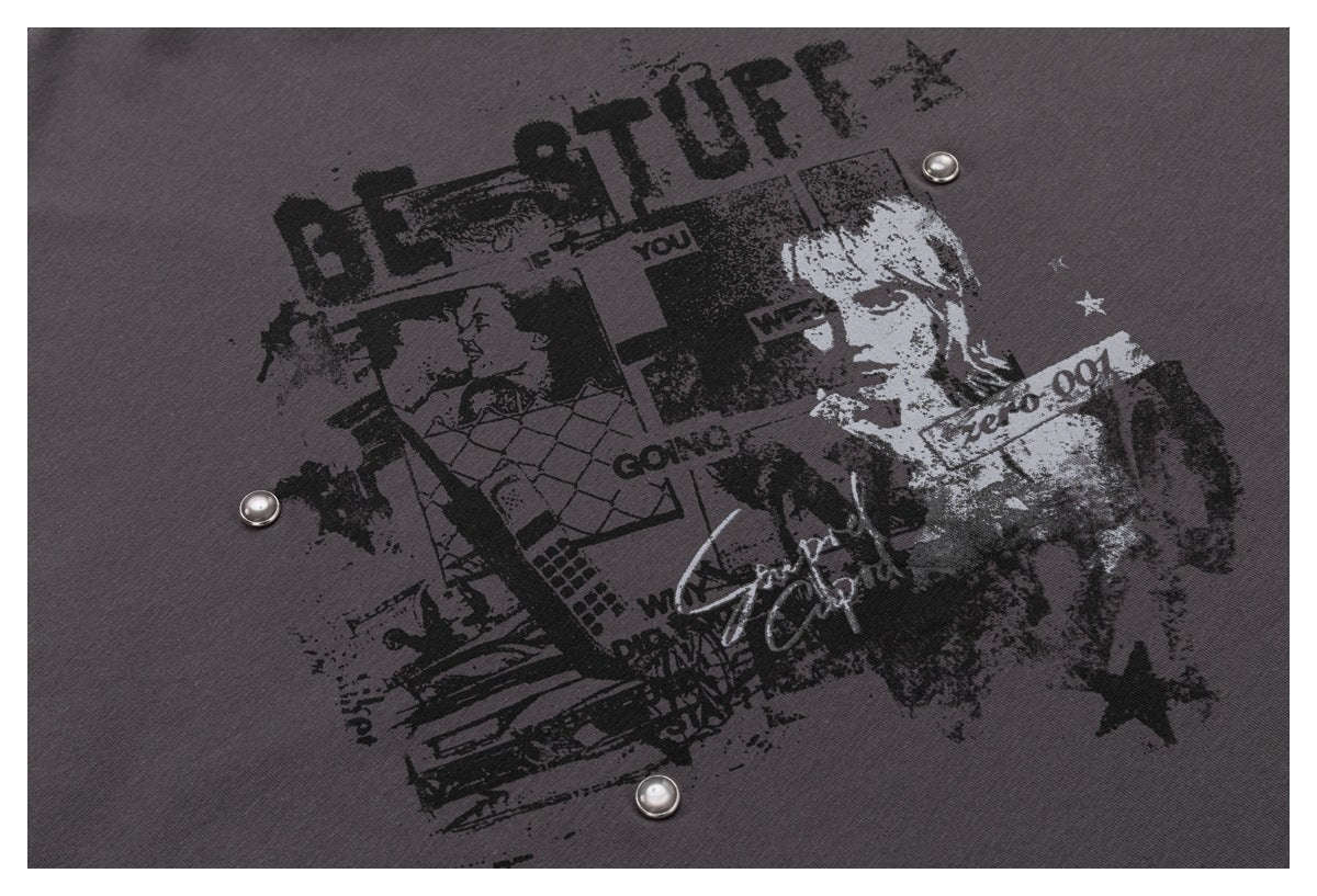 Close-up of a distressed black-and-white graphic print with metal studs on charcoal fabric.