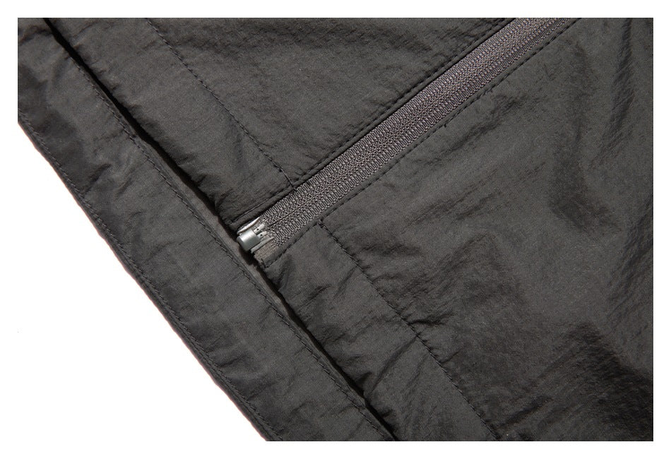 Close-up of a charcoal jacket zipper ending near a stitched side seam.