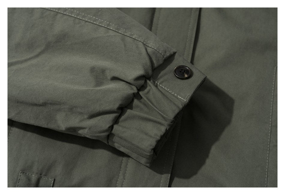 Close-up of an olive jacket sleeve cuff with a dark button and visible stitching.