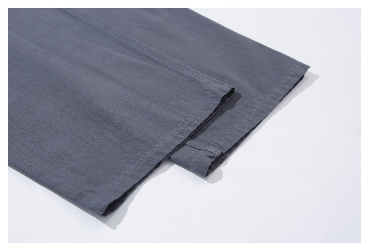 Close-up of the stitched hem on charcoal-gray trouser legs laid flat.