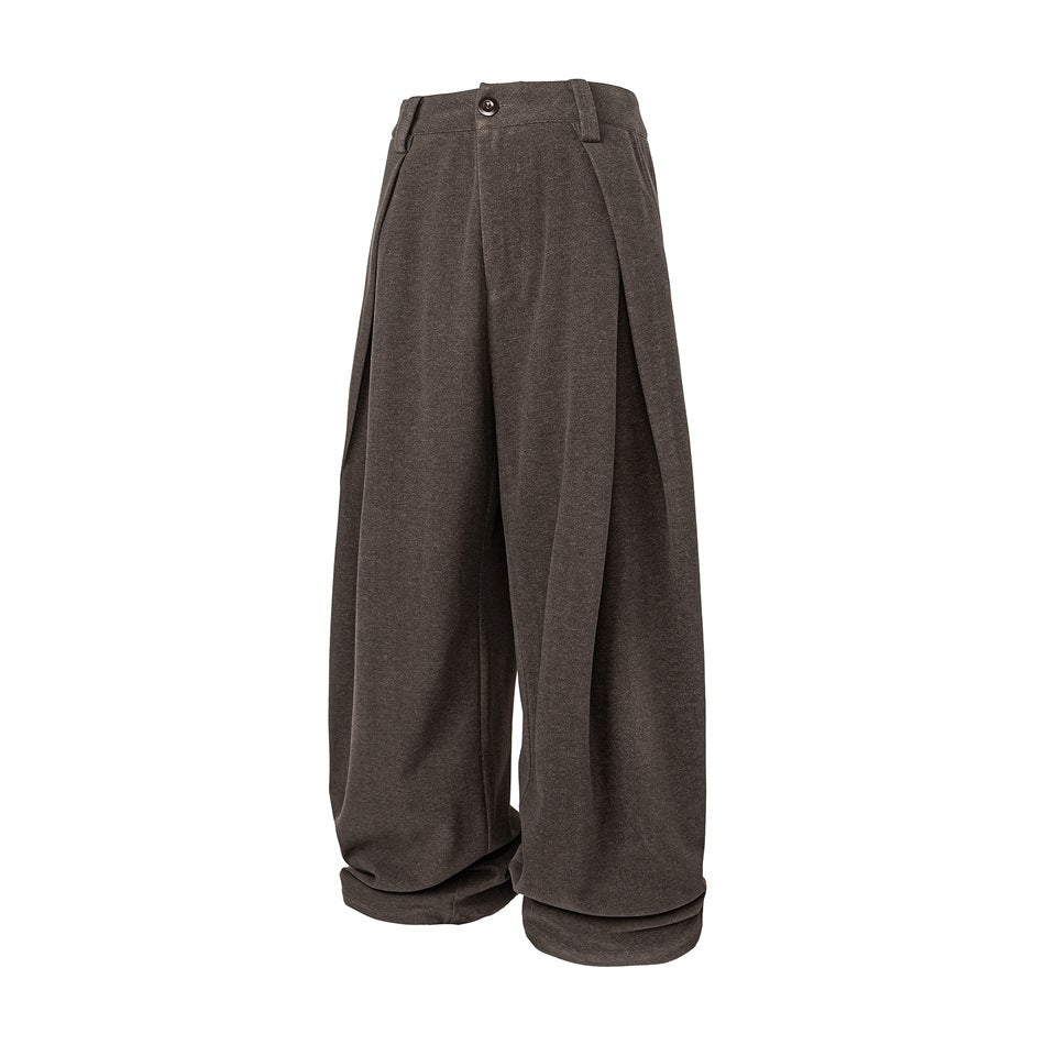 Brown wide-leg pleated trousers shown at an angle with a front button, large side-folding pleats and gathered cuffed hems