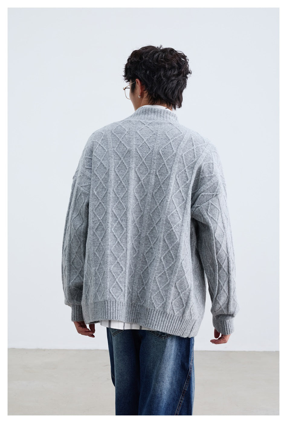 Rear view of a model wearing a light gray diamond-knit cardigan with ribbed cuffs and hem.