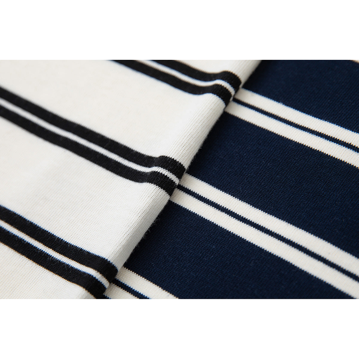 Close-up of white fabric with dark stripes beside navy fabric with white stripes.