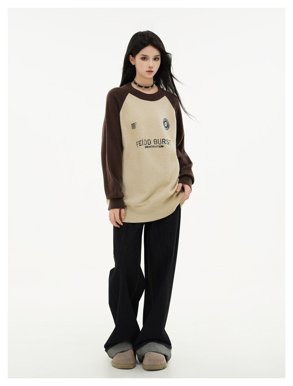 Three-quarter view of a model wearing a cream sweater with dark brown raglan sleeves and front lettering.