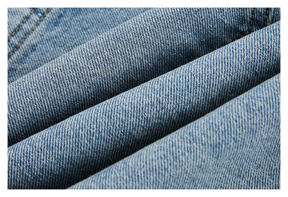 Extreme close-up of the woven texture of light blue denim folded into soft ridges.