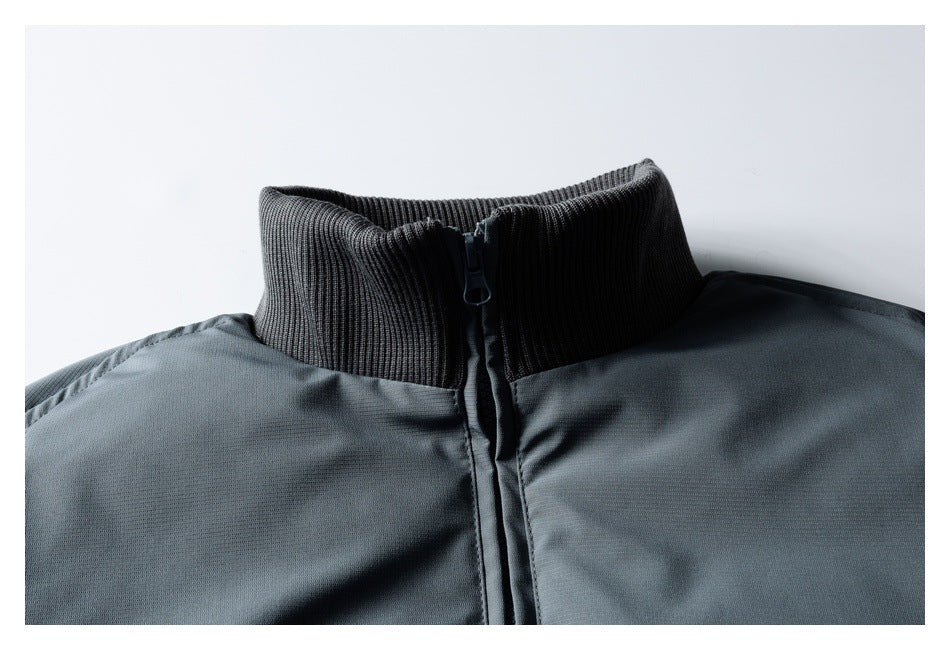 Close-up of a charcoal gray jacket with a ribbed stand collar and front zipper.