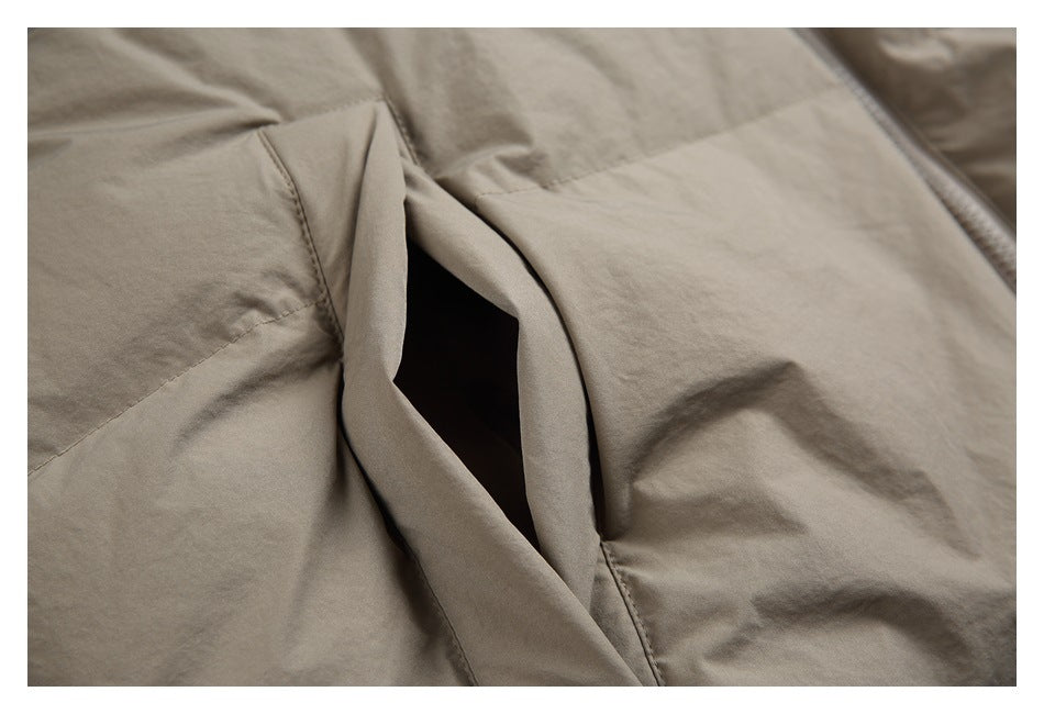 Close-up of a taupe jacket's angled pocket opening and stitched seams.