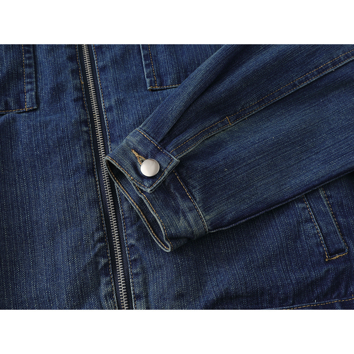 Close-up of a dark blue denim jacket sleeve cuff with a silver button beside the front zipper.
