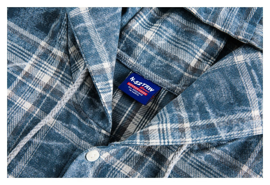 Close-up of the shirt's plaid collar, white button, and sewn-in blue neck label.