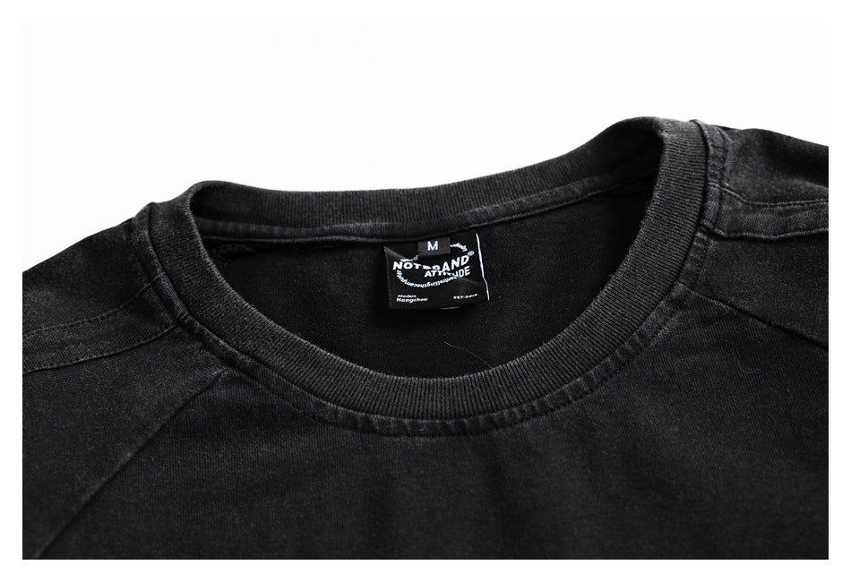 Close-up of the black T-shirt's ribbed crew neck, shoulder seams, and sewn neck label.
