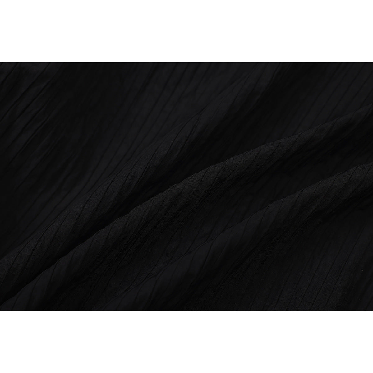 Close-up of black shorts fabric with fine vertical texture and folds.