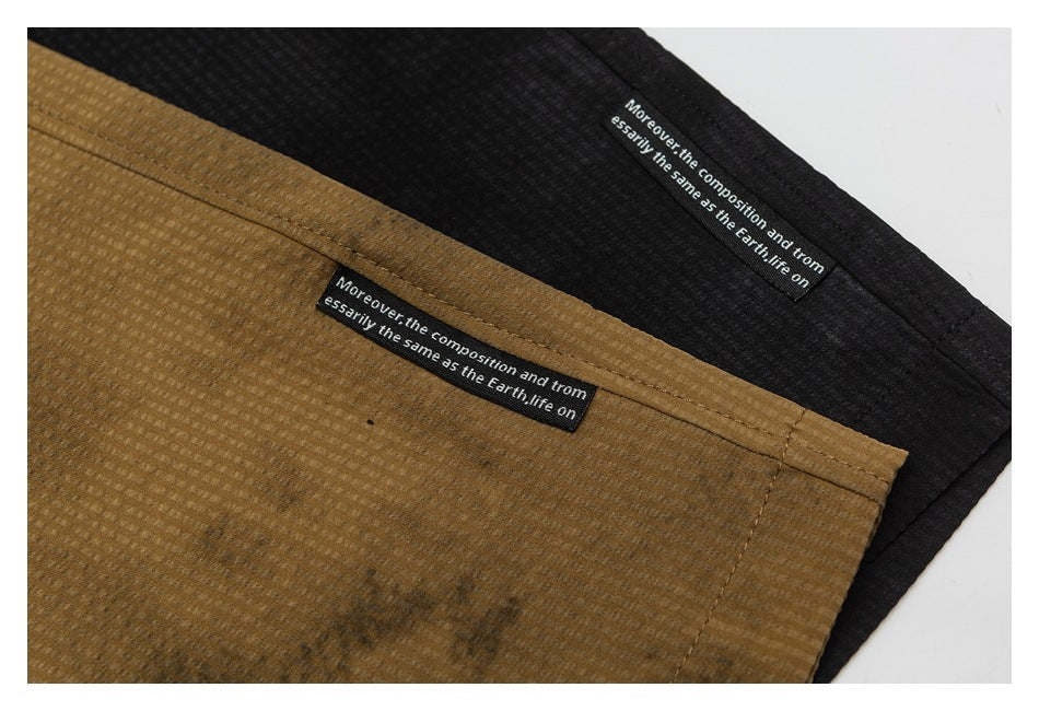 Close-up of ochre-brown and black shorts with small black sewn-in labels bearing white English text.