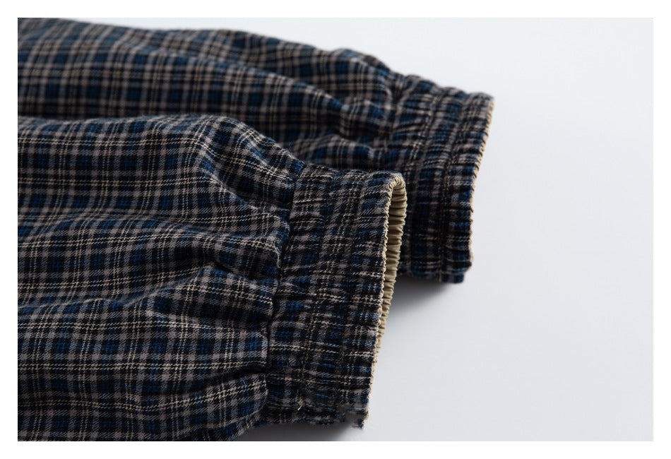 Close-up of two gathered edges on dark plaid fabric, showing the blue, beige, and black check pattern.