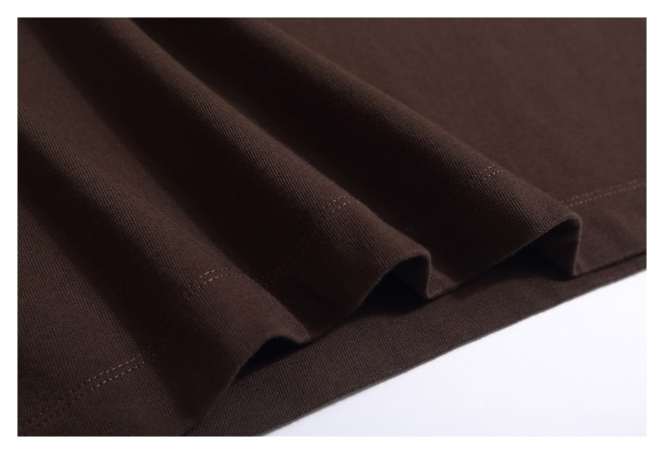 Close-up of dark brown shirt fabric gathered to show its folds and hem stitching.
