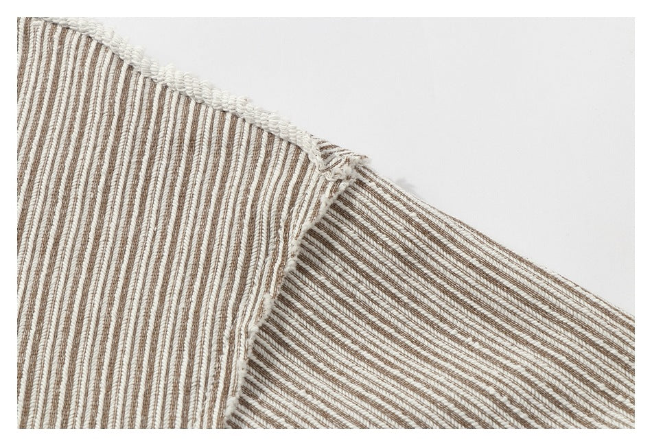 Close-up of a cream and brown narrow-striped garment seam with white overlock stitching.