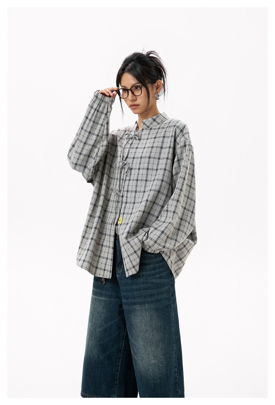 Model in a gray plaid tie-front blouse with balloon sleeves and dark wide-leg jeans, shown from the front.