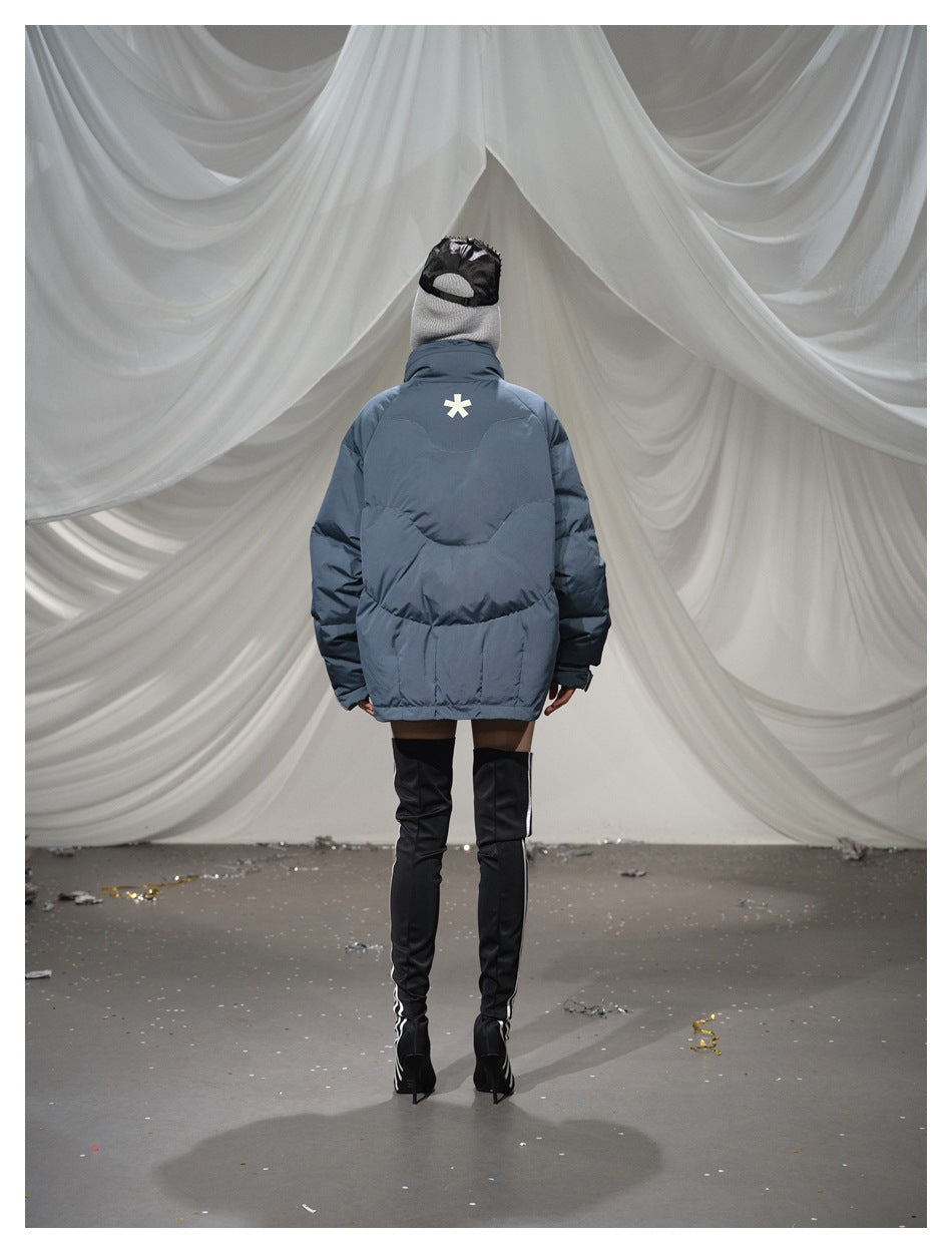 Back view of a model in a blue-gray quilted puffer jacket with a small white star-shaped mark at the upper back.