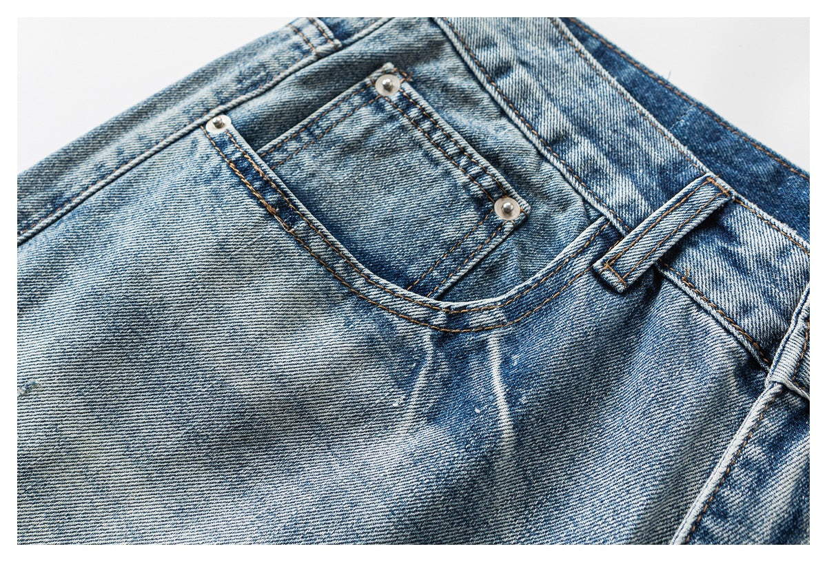 Close-up of blue faded jeans showing the front coin pocket, rivets, stitching and belt loop.